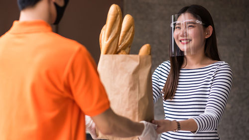 Rear view of delivery person delivering parcel to woman