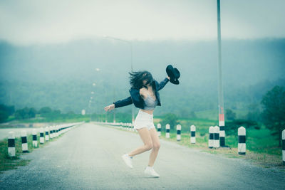 Full length side view of woman walking on road in city