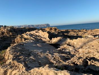 Rocks on beach against clear sky