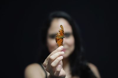 Close-up of hand holding leaf against black background