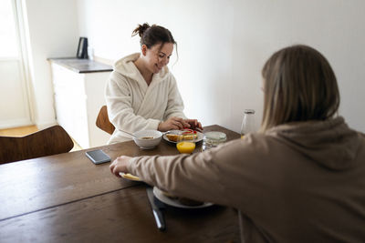 Happy young lesbian couple eating breakfast together at dining table