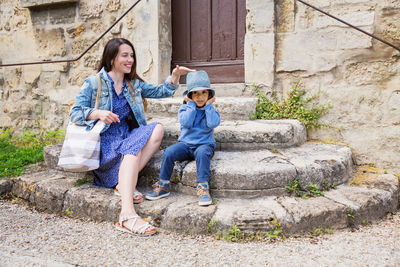 Mother and little handsome baby boy sitting on ancient stone stairs