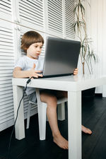 Cute boy using laptop at table