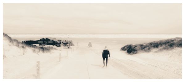 Rear view of person walking on sand at beach