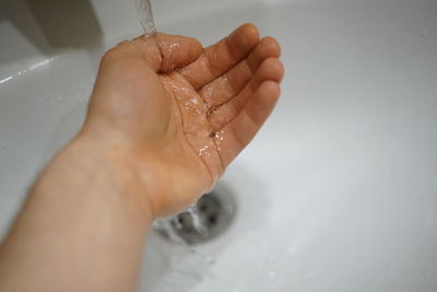 Close-up of hand touching water in bathroom