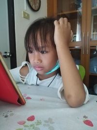 Portrait of cute girl lying on table at home