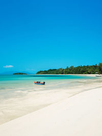 Scenic view of beach against clear blue sky