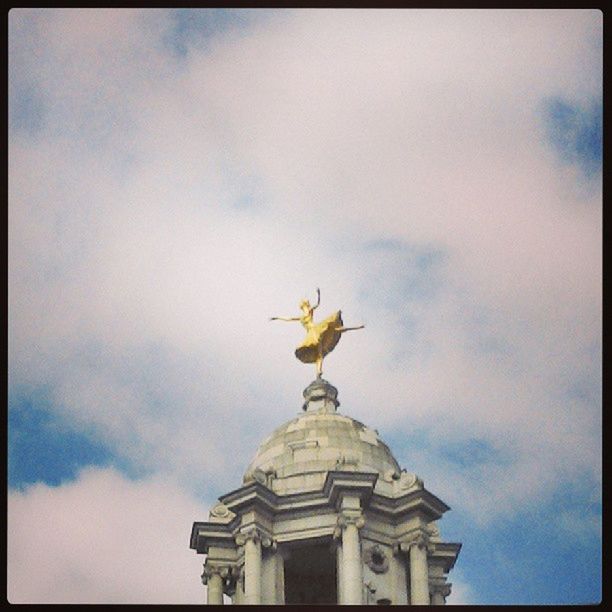 low angle view, sky, transfer print, statue, architecture, cloud - sky, built structure, auto post production filter, sculpture, building exterior, human representation, art and craft, cloudy, art, cloud, bird, creativity, high section, animal representation