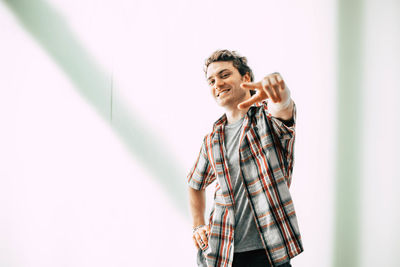 Man holding camera while standing against wall