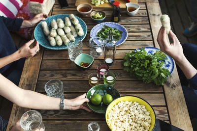 Cropped image of friends having food at table in log cabin