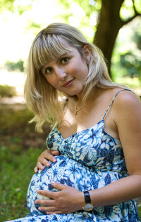 Portrait of beautiful pregnant woman in park
