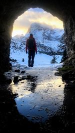 Rear view of man standing on rock against sky