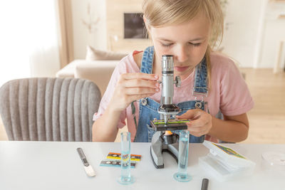 Girl looking through microscope at home