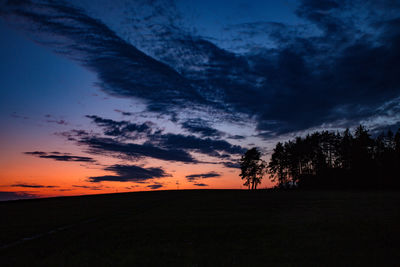 Silhouette trees on field against sky at sunset