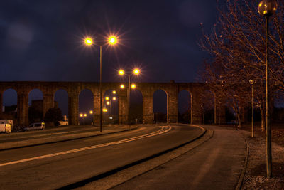 Illuminated road against sky at night