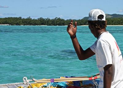 Man sitting on boat in sea against sky