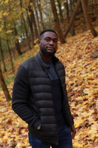 Portrait of young man standing in forest during autumn