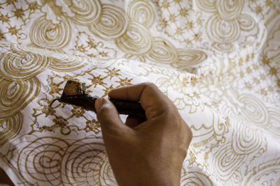 Close-up of hand holding canting. canting is tool to mke batik