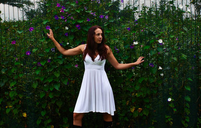 Full length of a young woman standing against flower wall