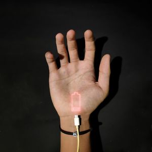 Cropped hand of man with low battery indication against black background