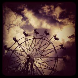 Low angle view of ferris wheel against cloudy sky