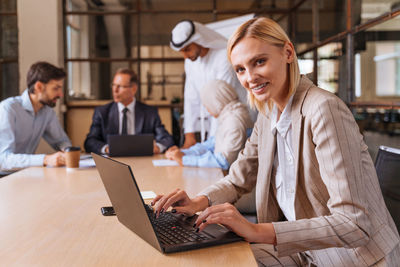 Businesswoman using laptop while sitting on table