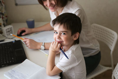 Happy mother is engaged in a laptop with her son preschooler, a real european interior, 