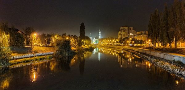 River amidst illuminated buildings against sky at night