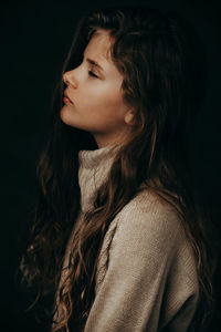 Side view of cute girl with eyes closed against black background