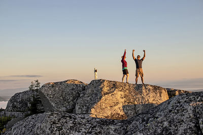 People standing on rock against sky