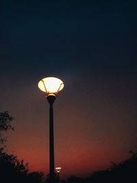 Low angle view of illuminated street light against dramatic sky