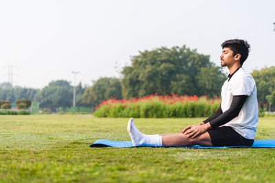 Young man using laptop while sitting on field