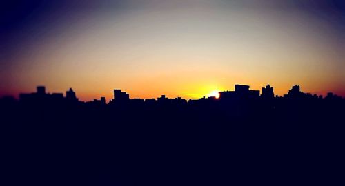 Silhouette buildings against sky during sunset