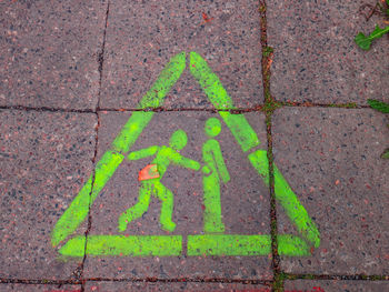 High angle view of green arrow sign on sidewalk