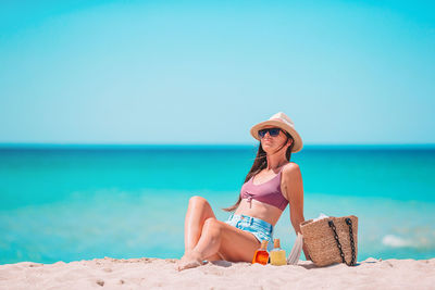 Full length of young woman sitting on beach