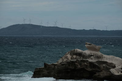 Traditional windmill by sea against sky