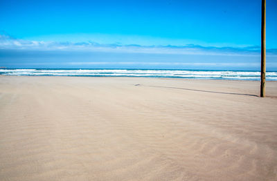 Scenic view of beach against blue sky