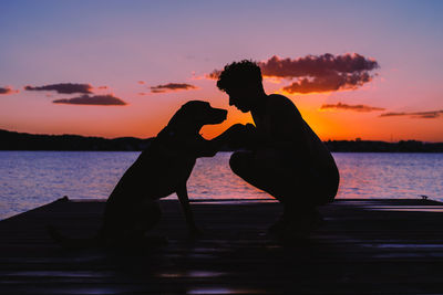 Silhouette couple against orange sky during sunset