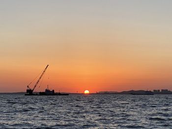 Silhouette sailboats in sea against sky during sunset