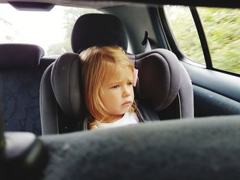 Sad girl looking away while sitting in car