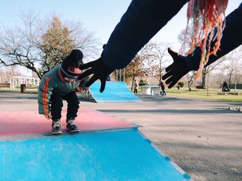 Cropped hands of parent reaching son in playground