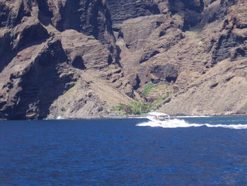 Scenic view of sea by mountain against sky