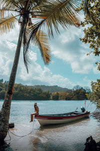 Rear view of man on boat on beach against sky