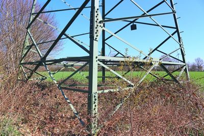 Rusty metal fence on field against clear blue sky