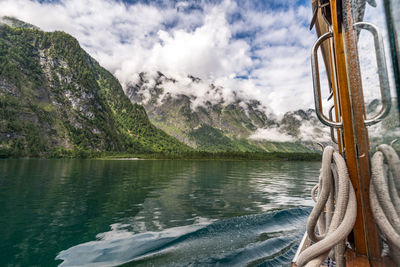 Scenic view of boat in lake by mountains against sky