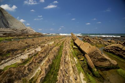 Scenic view of cliff by sea against sky