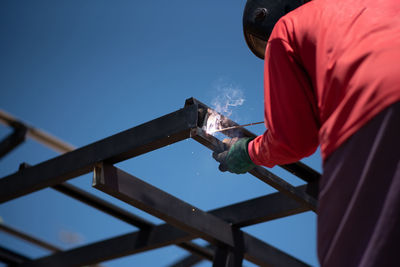 Man working on metal against sky