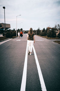 Rear view of woman walking on road