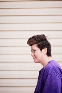 Smiling woman wearing eyeglass against wall