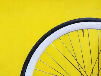 Close-up of bicycle wheel against yellow wall